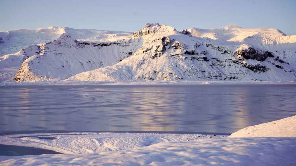 snow covered mountain near body of water