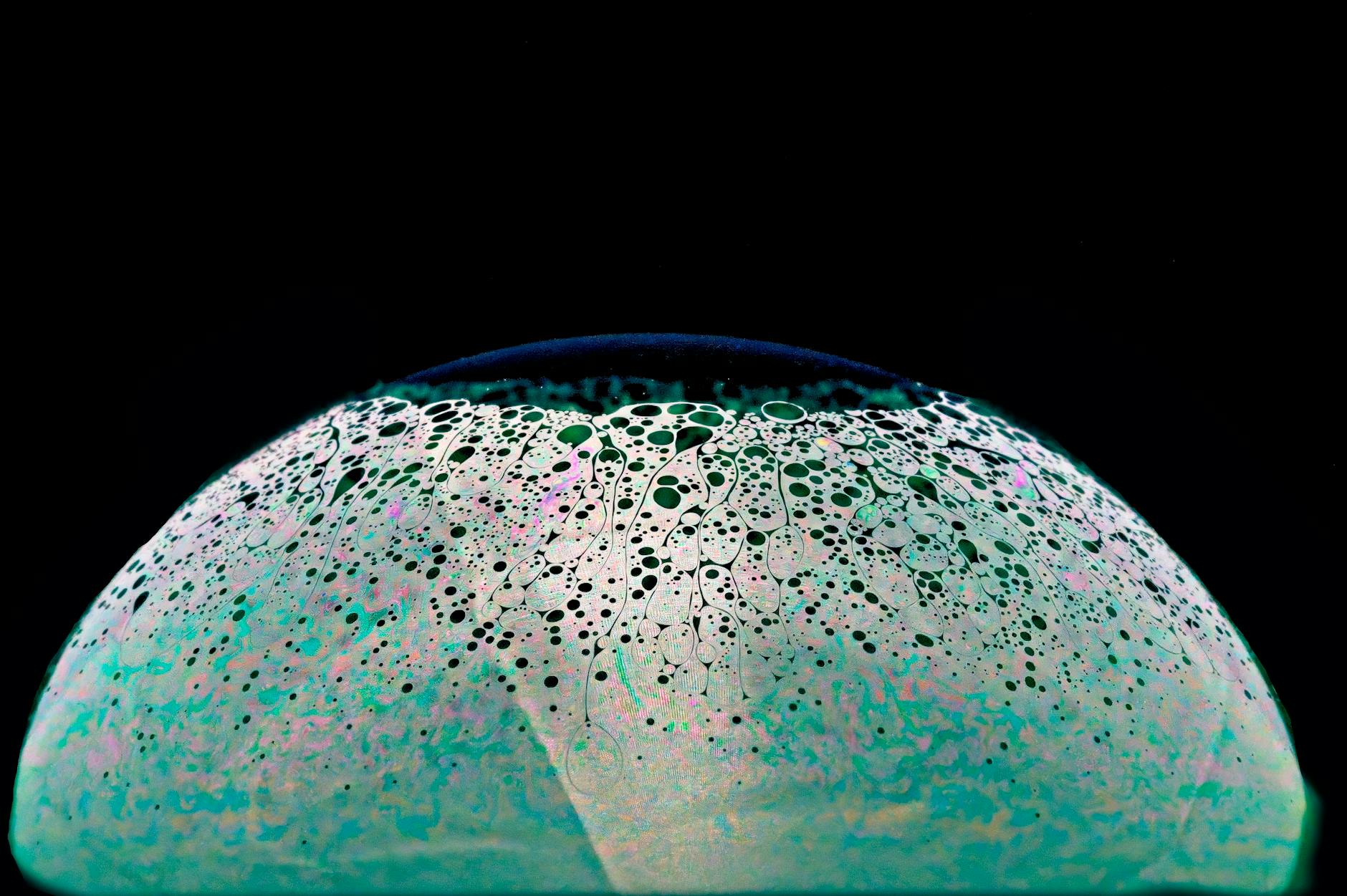 a glass ball with a green and blue speckled surface