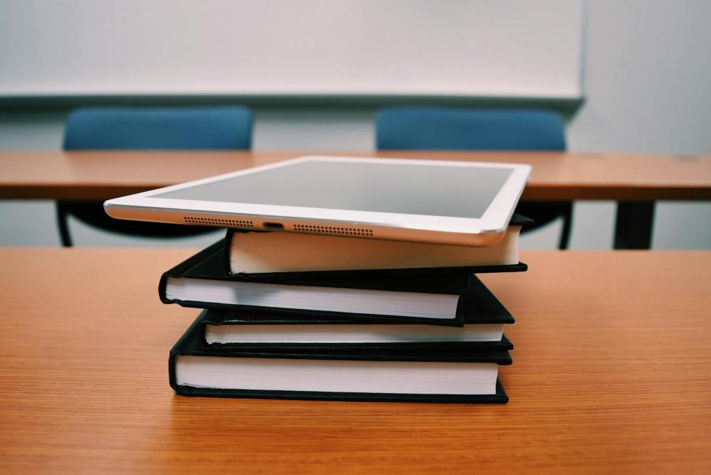 silver ipad on stack of books