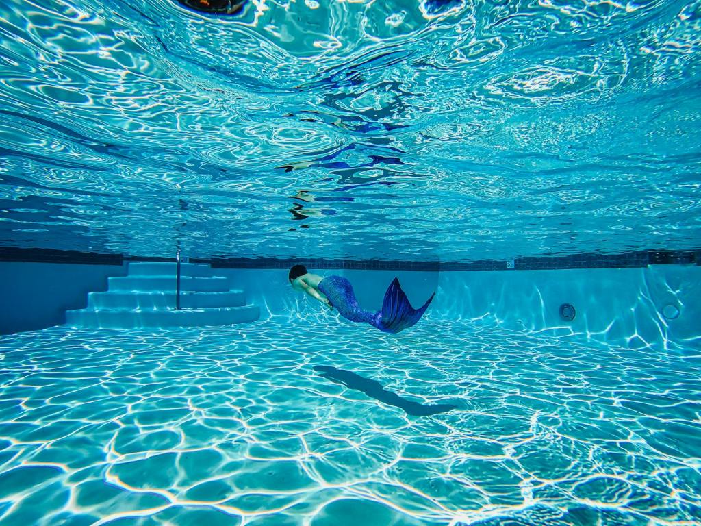 person wearing a mermaid suit swimming underwater