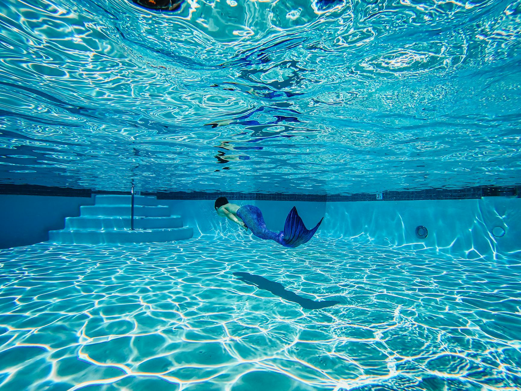 person wearing a mermaid suit swimming underwater