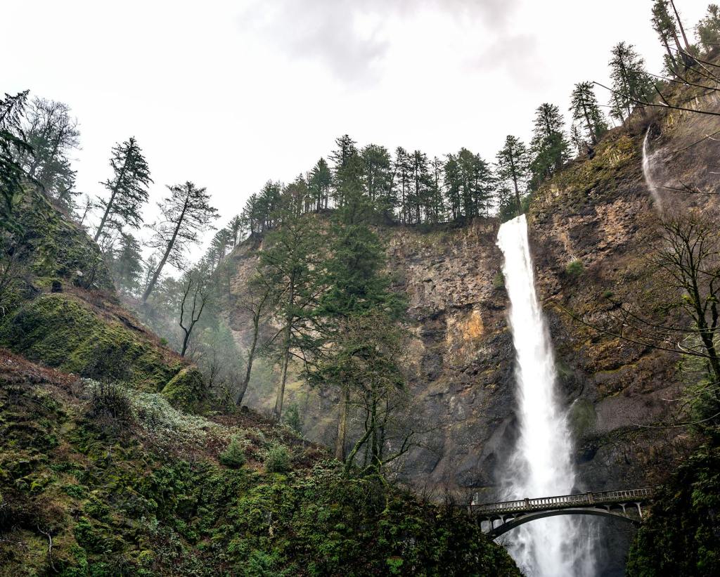 scenic landscape of rapid waterfall streaming in rocky gorge on cloudy day